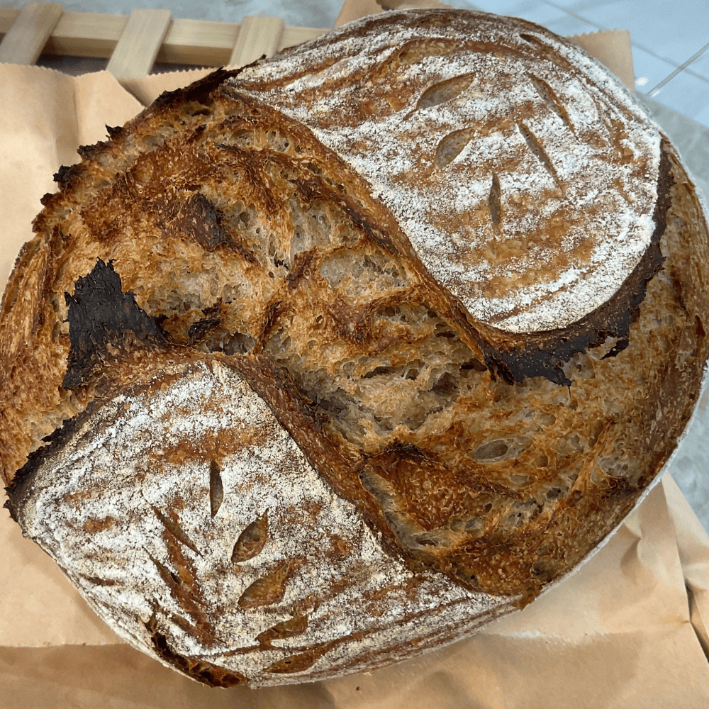 Two loaves of bread on brown paper with a tiled floor in the background
