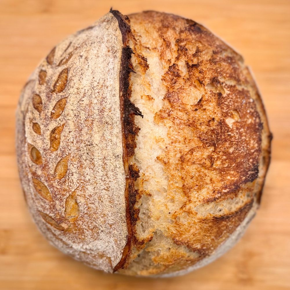 Loaf of bread with a cracked top on a wooden surface