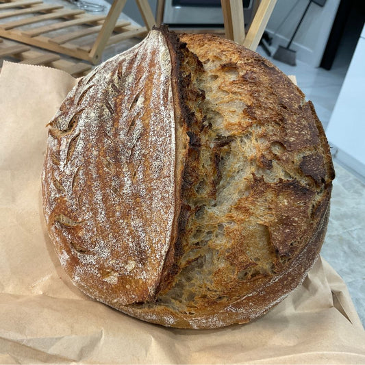 Loaf of bread on brown paper with a blurred indoor background